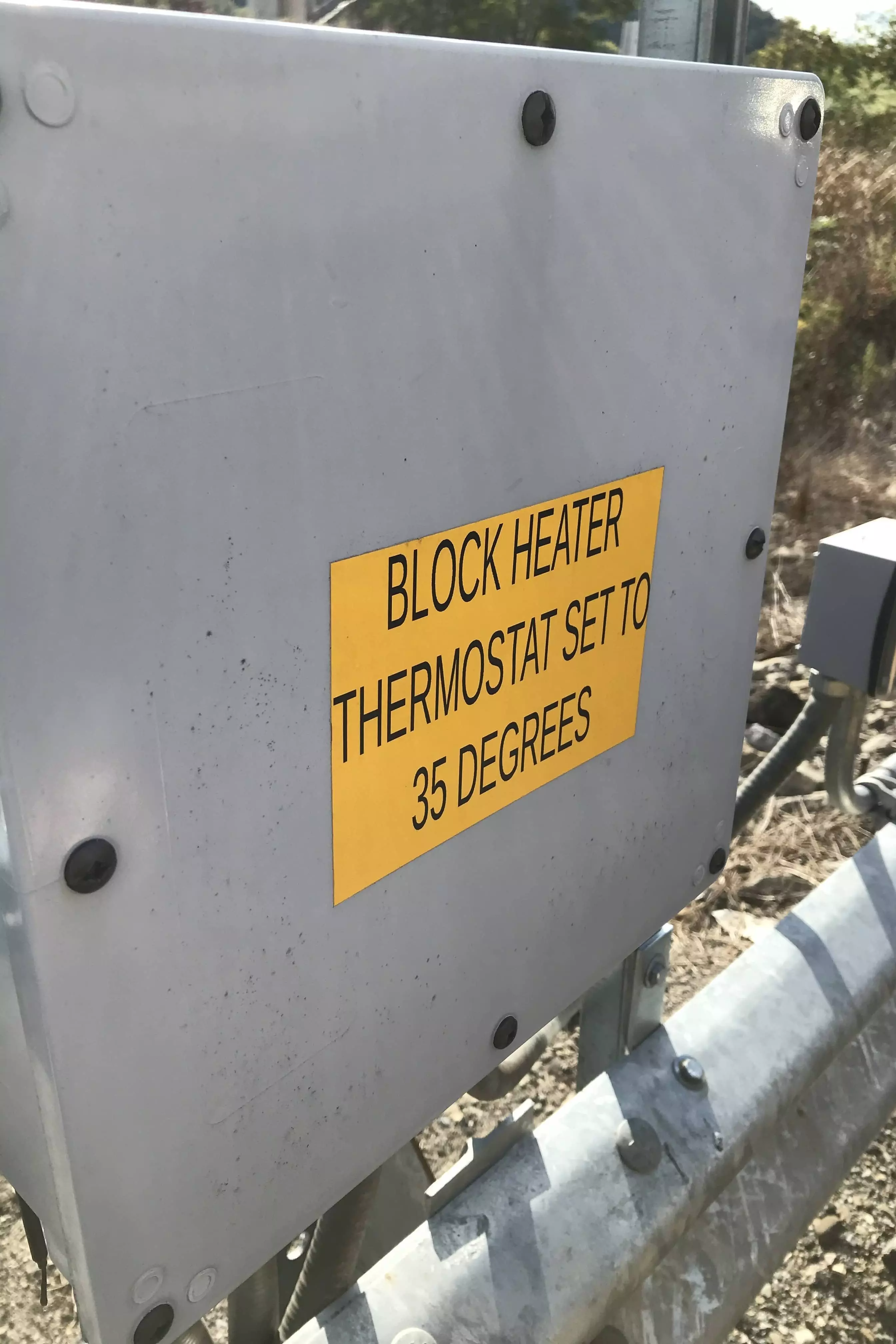 Electrical panel box with a yellow sign stating, 'Block Heater Thermostat Set to 35 Degrees.'